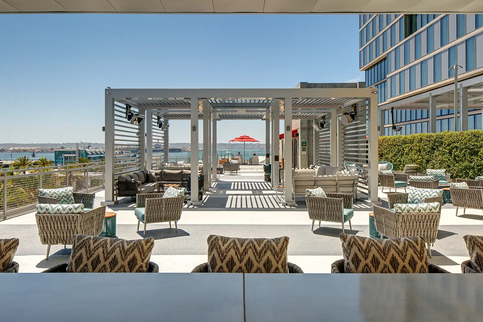 Hotel rooftop bar and lounge with modern seating, ambient lighting, and panoramic city views at sunset.