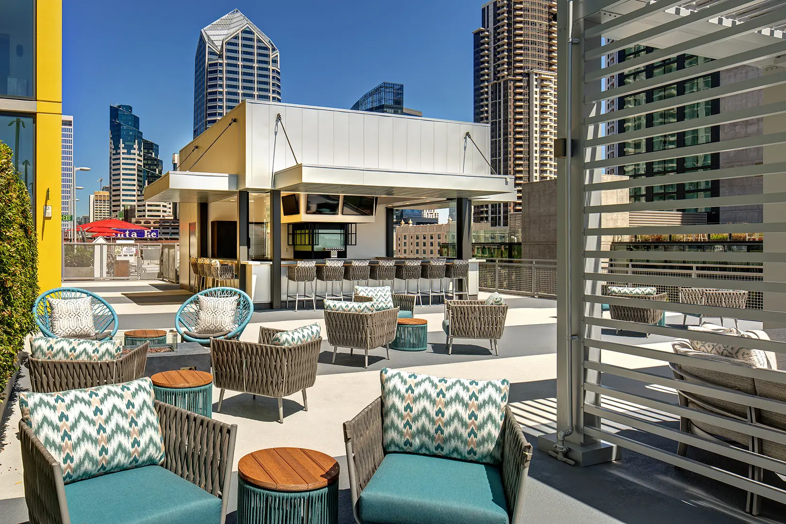 Stylish rooftop bar at a hotel with lounge seating, string lights, and sweeping city views at dusk.